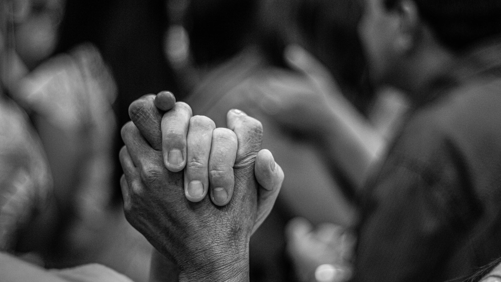 Ein Bild in schwarz-weiß, auf dem zwei Menschen ihre Hände halten.