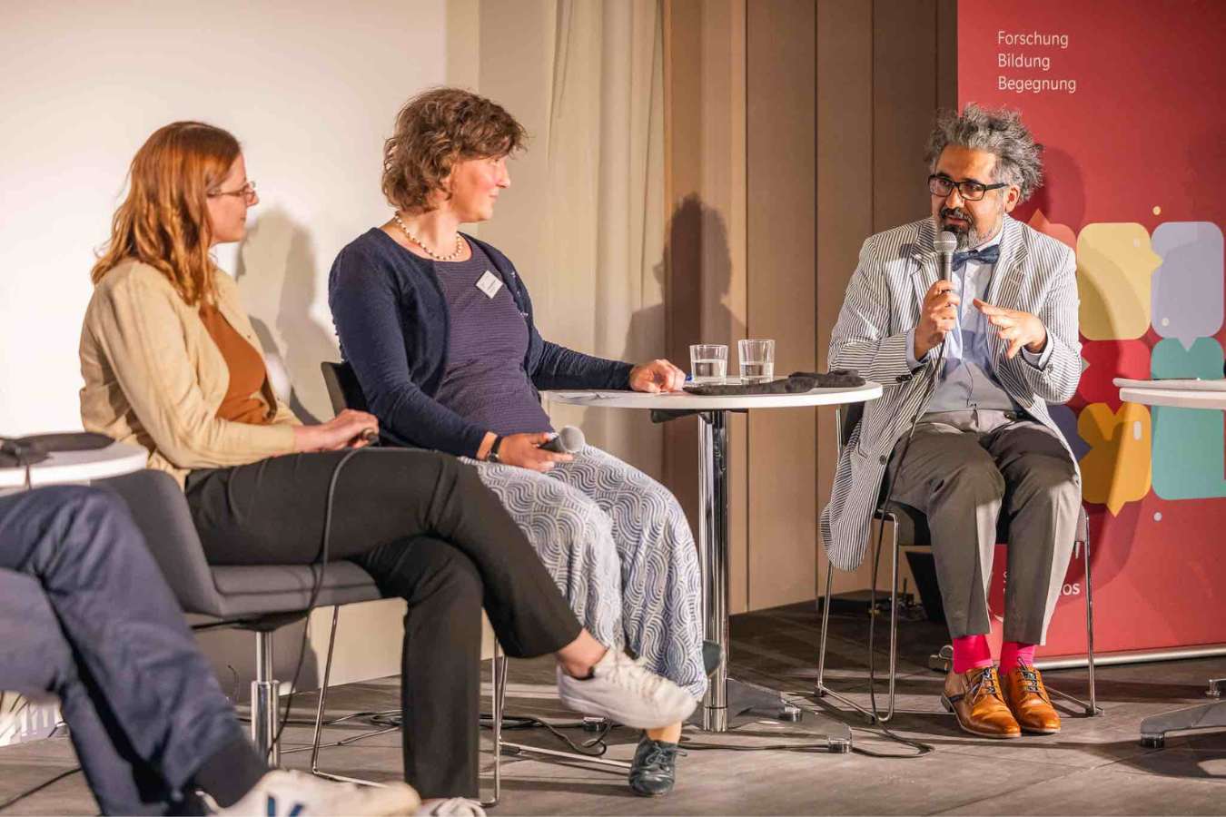 Menschen auf dem Podium diskutieren.