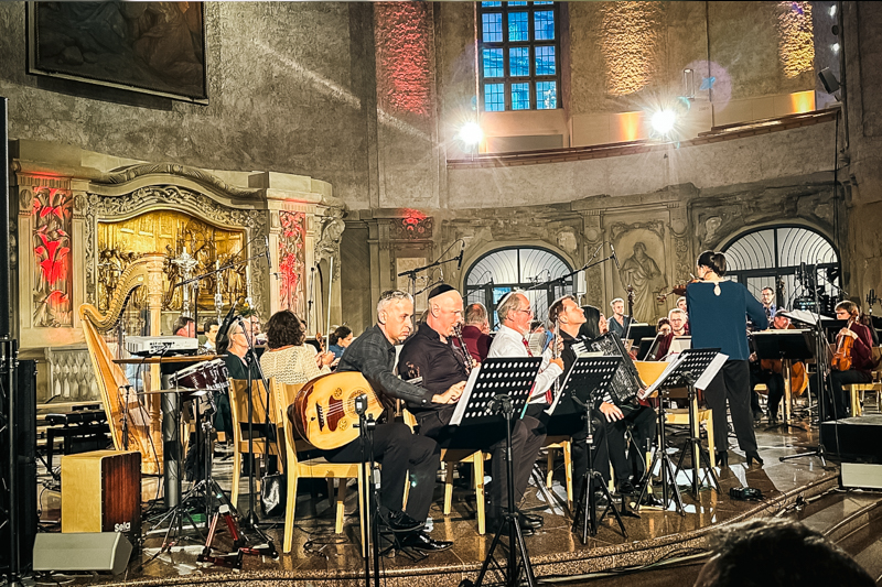 In einer hell erleuchteten Kirche spielen unterschiedliche Künstler*innen einen Konzert.